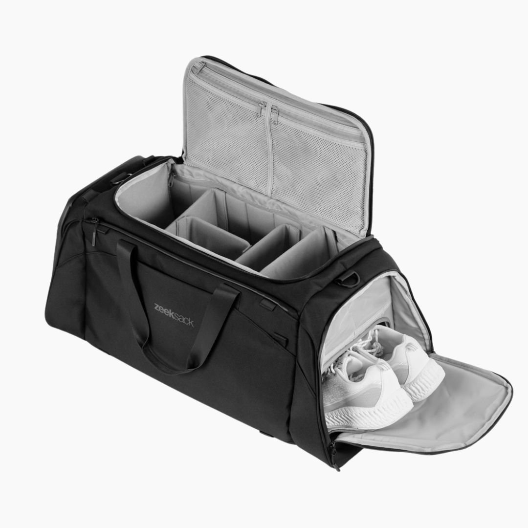 Czarna torba duffel z przegródkami i oddzielną kieszenią na buty z białymi butami.