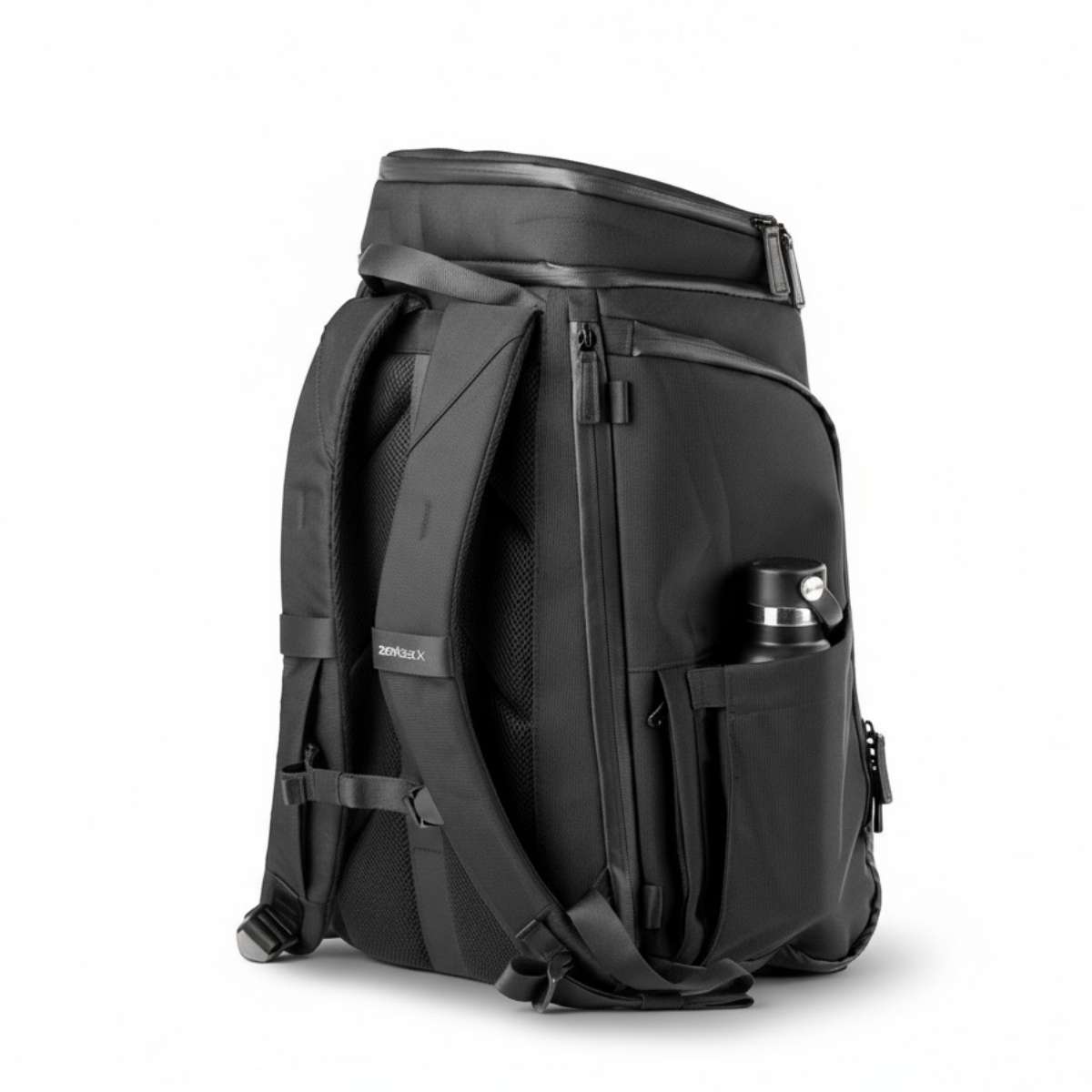 Czarny plecak z boku, zamknięte komory, butelka w kieszeni bocznej.