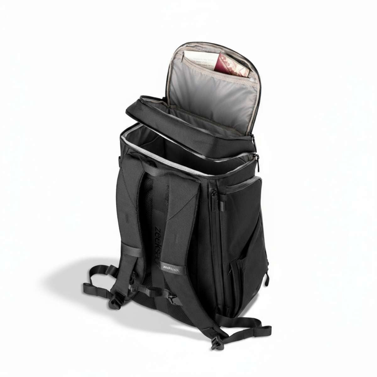 Czarny plecak z boku, stoi na podłodze z częściowo otwartą górną komorą.